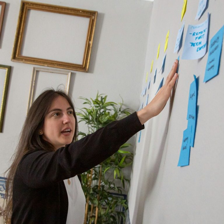 Explication médiation Femme présentant des notes autocollantes sur un mur, illustrant un brainstorming.